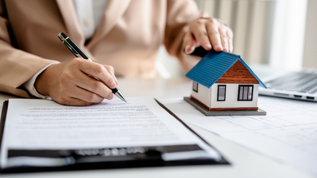 Person signing papers with a house