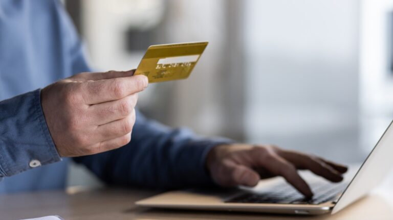 Man holding credit card while on computer