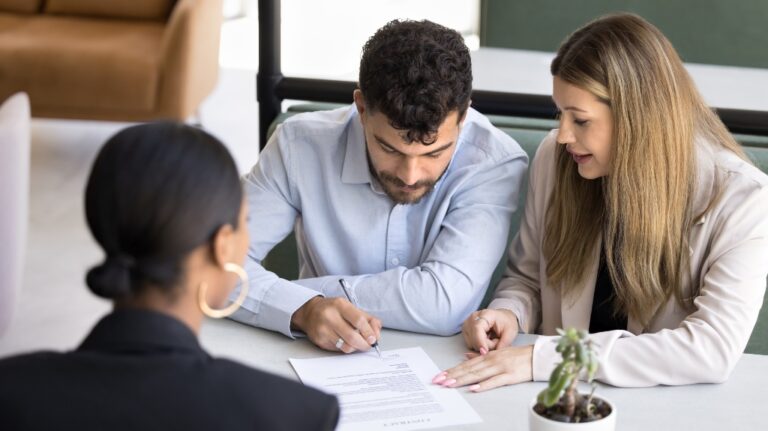 married couple signing document with lawyer