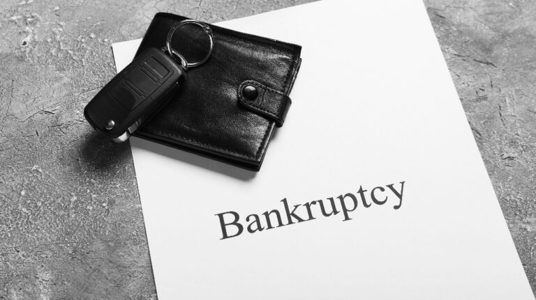 Wallet, car key and paper sheet with word Bankruptcy