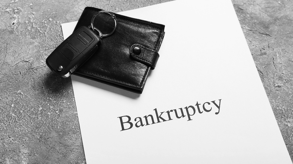 Wallet, car key and paper sheet with word Bankruptcy